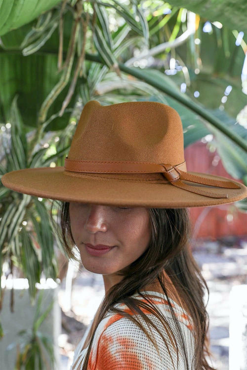 Woman wearing a brown wide-brimmed hat with a blurred natural background