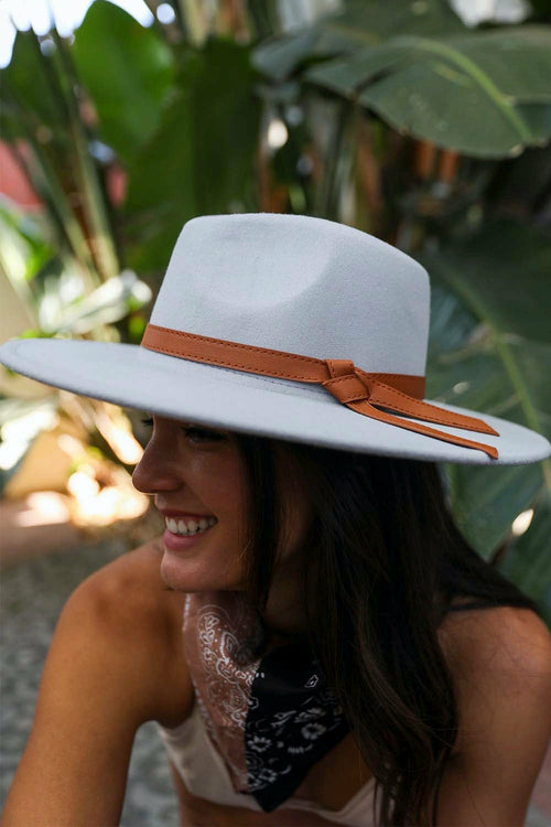 Woman wearing a white hat with a brown band in a tropical setting