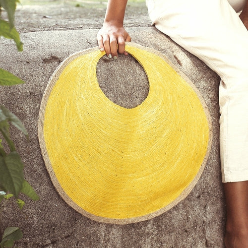 Yellow circular mat held by a person on a stone surface
