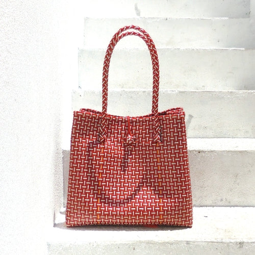 Red woven handbag on a light wooden surface