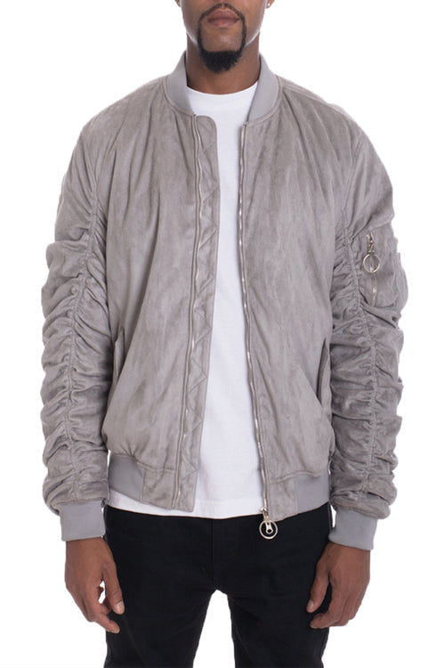 Man wearing a gray bomber jacket over a white shirt on a white background