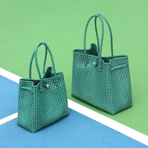 Two green woven handbags on a blue and green striped surface