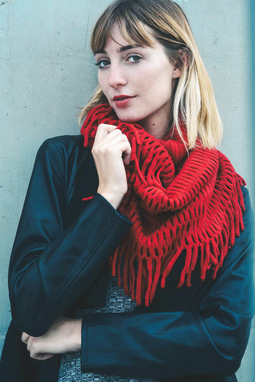 Woman wearing a red knitted scarf against a light blue wall