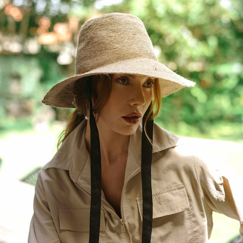 Woman wearing a wide-brimmed hat and beige jacket outdoors