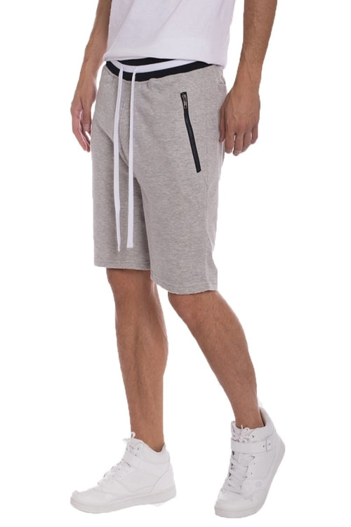 Person wearing gray shorts with a white background