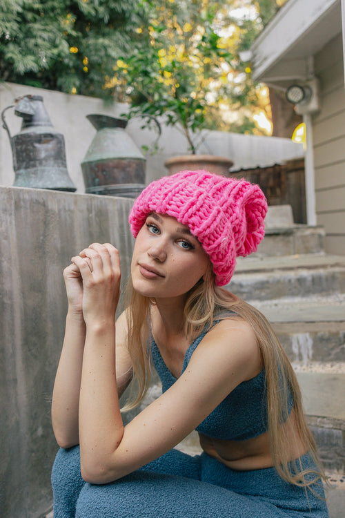 Woman wearing a pink knit hat sitting on steps outdoors