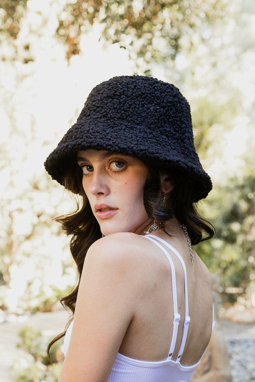 Woman wearing a black bucket hat with a blurred floral background