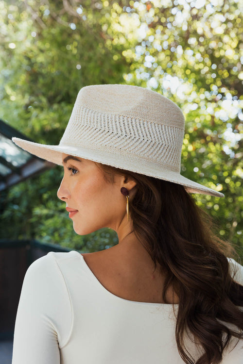 Woman wearing a beige hat with a blurred green background