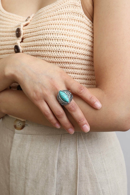 Person wearing a turquoise ring on a neutral background