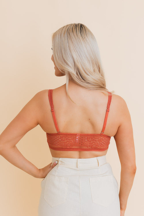 Woman wearing a red lace top against a beige background