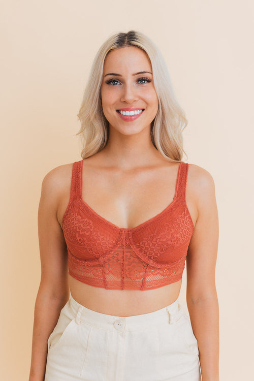 Woman wearing a red lace bralette against a beige background