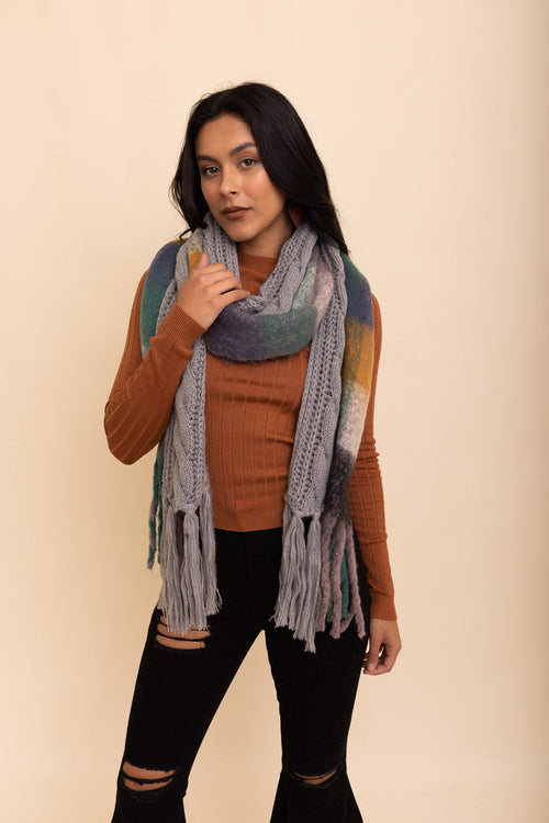 Woman wearing a colorful scarf and brown sweater against a beige background