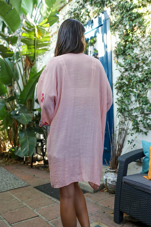 Woman wearing a pink cover-up standing in a garden setting