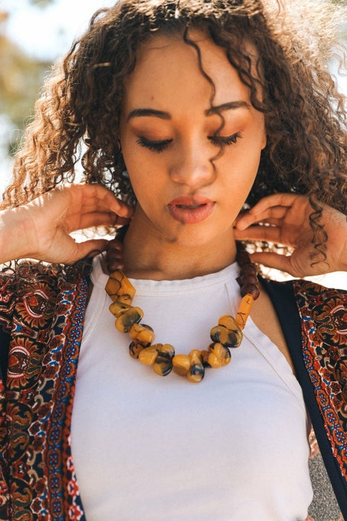 Woman wearing a patterned cardigan and a necklace with a blurred background