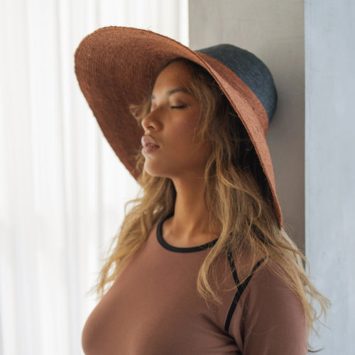 Woman wearing a wide-brimmed hat with a neutral background