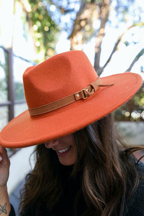 Person wearing an orange hat with a brown band outdoors