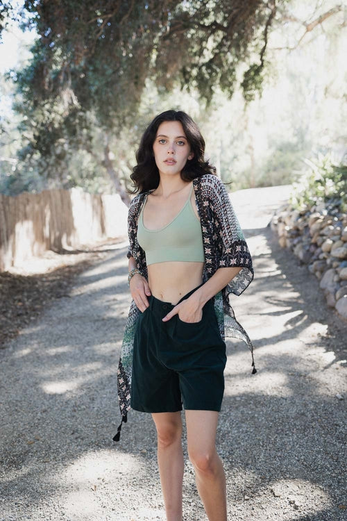 Woman standing on a gravel path with greenery in the background