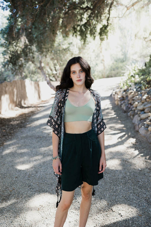 Woman standing outdoors on a gravel path with trees and rocks in the background