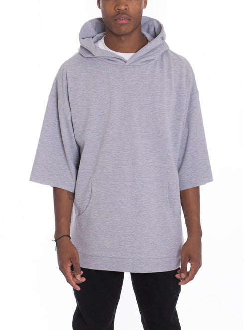Person wearing a gray hoodie with short sleeves on a white background