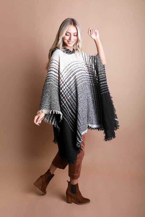 Woman wearing a black and white patterned poncho against a beige background