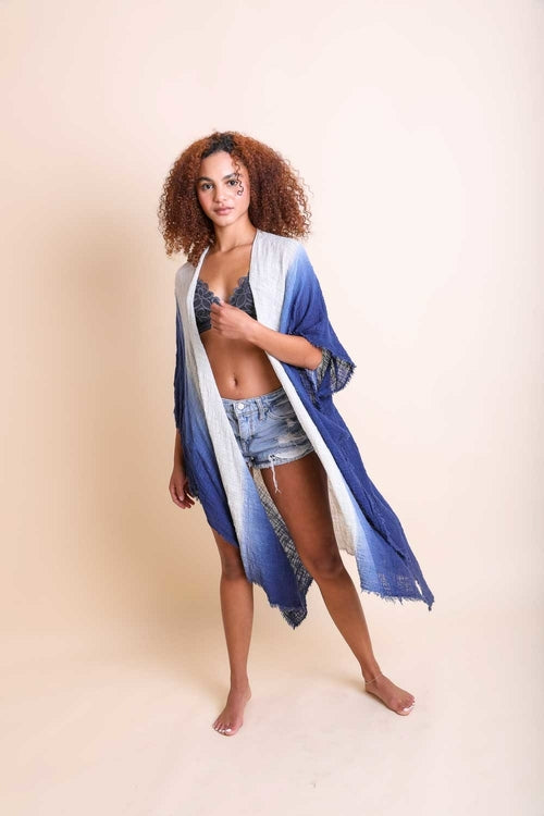 Woman wearing a blue kimono over a white garment on a beige background