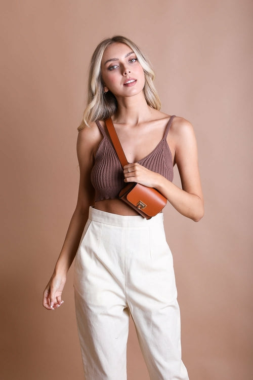 Woman holding a brown handbag against a beige background