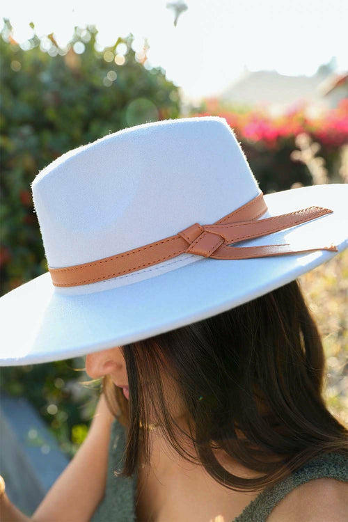 Light blue hat with a brown band worn by a person outdoors.